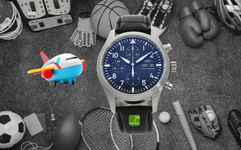 iwc-fliegeruhr-vor-sportsachen-und-ein-bunter-spielzeugflieger-fliegt-in-richtung-der-uhr